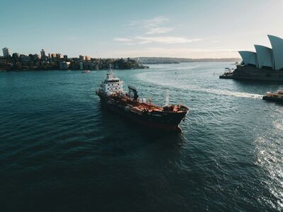 Een schip vaart door de haven met de Sydney Opera House op de achtergrond onder een heldere lucht.
