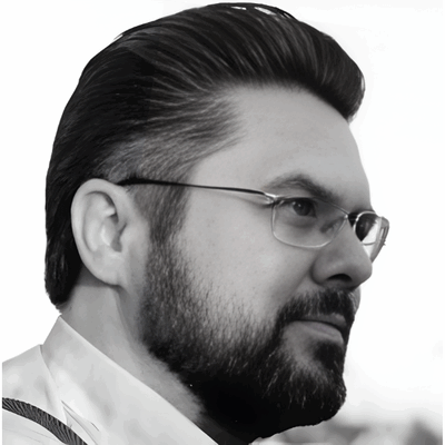 Profiel van een man met een baard en bril, met een stijlvolle kapsel, in zwart-wit.